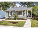 Charming one-story home with gray siding, landscaped yard, and covered porch with seating area at 1257 Lyle Pl, Atlanta, GA 30318