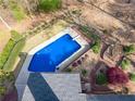 Aerial view of a sparkling blue swimming pool surrounded by lush landscaping and a wooden pergola at 2121 Rock Court, Loganville, GA 30052