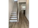 Staircase with wood railing and carpeted steps leading to the upper level, bathed in natural light at 76 Mayhaw Pt, Sharpsburg, GA 30277
