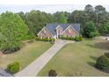 Traditional brick home with a well-manicured lawn and driveway surrounded by mature trees at 3541 Haddon Hall Dr, Buford, GA 30519