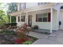 Inviting front porch with red door and shutters, surrounded by lush landscaping and a paved walkway at 4314 Saddlecreek Ct, Auburn, GA 30011