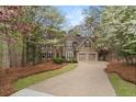 Two-story home with stucco and stone exterior, mature trees, and an inviting driveway at 525 Sycamore Pt, Woodstock, GA 30189