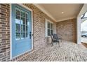 Inviting covered porch with brick flooring and a stylish blue front door at 4405 Croftshire Pl, Cumming, GA 30040