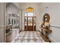 Elegant foyer with checkerboard floors, a wooden door, and a stylish chandelier with an archway leading to the dining area at 1304 Marietta Country Club Nw Dr, Kennesaw, GA 30152