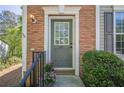 Close-up of the front door with brick surround and decorative plants and black railing at 9155 Nesbit Ferry Rd # 65, Alpharetta, GA 30022