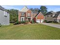 Traditional two-story brick home with a manicured lawn, trimmed hedges, and attached two car garage at 1721 Telfair Chase Way, Lawrenceville, GA 30043
