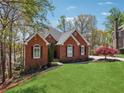 Brick home featuring a manicured lawn and mature trees surrounding the property at 6060 Masters Club Dr, Suwanee, GA 30024