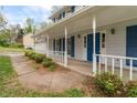 Inviting front porch with white railing, blue door, and manicured greenery at 9992 Neuchatel Cres, Jonesboro, GA 30238