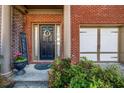 Inviting front entrance featuring a black door with wreath, brick columns and manicured landscaping at 1829 Appaloosa Mill Ct, Buford, GA 30519