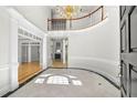 Elegant foyer features high ceilings, a curved staircase, hardwood floors, and decorative lighting at 545 Slane Trce, Roswell, GA 30076