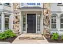 Close-up of the home's front door with sidelights and transom window, stone entryway, and decorative outdoor lighting at 545 Slane Trce, Roswell, GA 30076