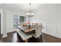Bright dining room featuring modern chandelier, wainscoting, and hardwood floors at 1895 Weston Ln, Tucker, GA 30084