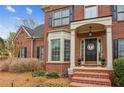 Welcoming brick home entrance featuring a covered porch, flowerpots and manicured bushes at 4155 Summit Gate Dr, Suwanee, GA 30024