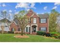 Stately brick home with manicured lawn and garden beds under a bright sky at 4155 Summit Gate Dr, Suwanee, GA 30024