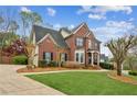 Beautiful red brick house with lush green lawn and mature trees in a suburban setting at 4155 Summit Gate Dr, Suwanee, GA 30024