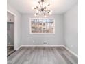 Bright dining room with modern light fixture, large window, and gray wood-look flooring at 3862 Northstrand Dr, Decatur, GA 30035