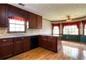 Kitchen features wood cabinetry, hardwood floors, neutral countertops, black appliances, and natural light from multiple windows at 1510 Wood Thrush Way, Marietta, GA 30062