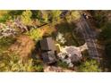 Aerial view of a home with a long driveway and fenced yard near mature trees and a paved road at 1718 Pucketts Sw Dr, Lilburn, GA 30047