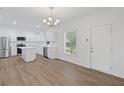 Bright kitchen featuring white cabinets, stainless steel appliances, a center island, and wood-look flooring at 3406 Randell Brown Avenue Unit 3, Atlanta, GA 30354