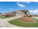 Low angle view of a well maintained yard and home with an attached garage and mature landscaping at 1170 Livery Cir, Lawrenceville, GA 30046