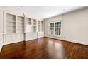 An empty living room featuring built-in shelving, hardwood floors, large windows, and detailed trim at 51 Ivy Chase Ne, Atlanta, GA 30342