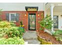 Close-up of home's entrance featuring brickwork, a covered entry, and manicured landscaping at 3075 Camden Way, Alpharetta, GA 30005