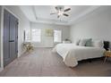 Relaxing main bedroom featuring a tray ceiling, carpet flooring, and a closet with gray double doors at 1494 Addison Pl, Decatur, GA 30033