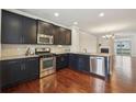 Open kitchen boasts stainless appliances, dark cabinetry, granite countertops, and hardwood floors throughout at 4934 Wyeth Way, Johns Creek, GA 30022