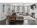 Stylish living room with dark wood floors, gray sectional, fireplace, and large windows for natural light at 5135 Arnold St, Covington, GA 30014