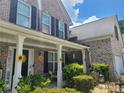The brick home's inviting front porch features white columns, dark shutters, and pretty landscaping at 828 Cooper Lakes Ct, Grayson, GA 30017