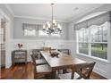 Bright dining room features hardwood floors, wainscoting, chandelier, and large windows at 5950 Thoroughbred Way, Suwanee, GA 30024