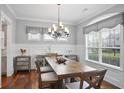 Well-lit dining room with modern chandelier, hardwood floors, and elegant window treatments at 5950 Thoroughbred Way, Suwanee, GA 30024
