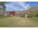 Ranch-style house featuring a red metal roof, a covered porch, and a well-maintained lawn at 6690 Pine Ridge Cir, Cumming, GA 30041