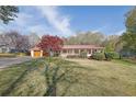 Charming home with red metal roof, front porch, and mature tree on a bright, partly cloudy day at 6690 Pine Ridge Cir, Cumming, GA 30041