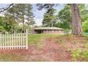 Quaint single-story home with a brick facade, surrounded by lush greenery and a charming white picket fence at 3221 Colquitt Dr, Atlanta, GA 30340