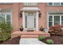 Elegant front porch with classic columns, stylish lighting, and charming potted plants by the front door at 1343 Riverview Run Ln, Suwanee, GA 30024
