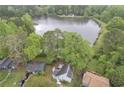 Beautiful aerial view of a quaint blue home next to a placid lake, surrounded by verdant trees and landscaping at 1077 Mainstreet Valley Dr, Stone Mountain, GA 30088