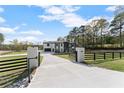 Stunning modern two-story home with a gated entrance and a long driveway in a lush, green setting at 1688 Mineral Springs Rd, Hoschton, GA 30548