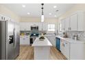 Modern kitchen with white cabinets, stainless steel appliances, and a center island with light wood floors at 3286 Sir Henry St, Atlanta, GA 30344