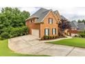 Brick home with an expansive driveway, lush green lawn, and well-manicured landscaping at 4020 Balleycastle Ln, Duluth, GA 30097