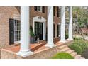 Inviting front porch of a brick home featuring elegant columns, black shutters, and stylish decorative accents at 6124 Kings Mountain Ct, Stone Mountain, GA 30087