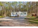 Single-story home with white trim, surrounded by a wooded lot and a gravel driveway at 2466 Monroe Jersey Rd, Covington, GA 30014