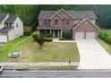 Two-story home with brick and siding, featuring a two-car garage and landscaped front yard at 1440 Gallup Dr, Stockbridge, GA 30281