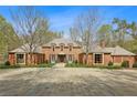 Expansive front exterior featuring a stately brick home with ample parking and mature trees at 4195 Woodland Brook Se Dr, Atlanta, GA 30339
