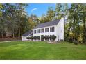 Charming two-story home featuring blue shutters, a well-manicured lawn, and mature trees in the background at 6493 Crooked Creek Pl, Lithonia, GA 30058
