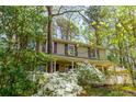 Charming two-story home with a welcoming front porch surrounded by mature trees and flowering azaleas at 6795 Brandon Mill Rd, Atlanta, GA 30328