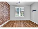 Cozy bedroom featuring a brick accent wall, hardwood floors, and a bright window, creating a warm and inviting space at 267 Castleberry Station Sw Dr, Atlanta, GA 30313