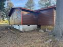 Exterior shot of the home showing the backyard, brown siding, and white painted cinder block foundation at 144 Flat Rock Rd, Oxford, GA 30054