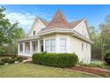 Charming yellow two-story home featuring a manicured lawn, front porch, and unique architectural details at 5732 Falls View Dr, Buford, GA 30518