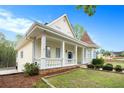 Charming yellow two-story home featuring a manicured lawn, front porch, and unique architectural details at 5732 Falls View Dr, Buford, GA 30518